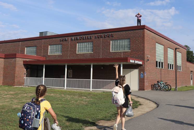 Bow Memorial School principal Adam Osburn stands on the roof to greet students arriving for the first day of school on Aug 29, 2022.