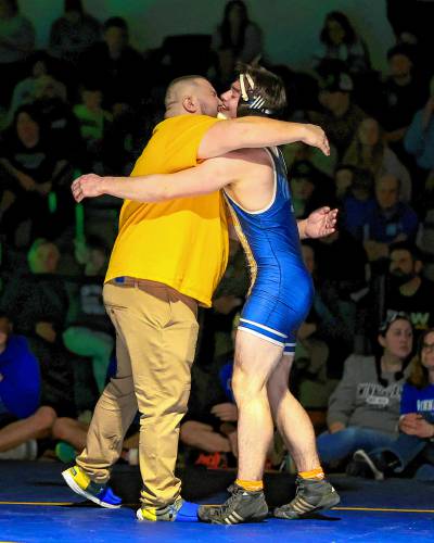 Bow’s Joe McDowell (right) and head coach Bill Chavanelle (left) embrace after McDowell’s win in the 175-pound finals at the Division III wrestling championship at Bow High School on Saturday. Bow claimed four individual titles and the team title.