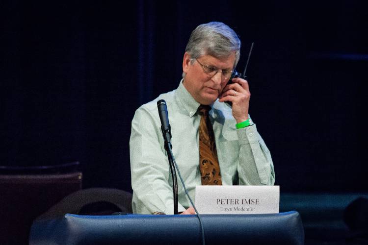 Town moderator Peter Imse uses a radio to communicate with an overflow crowd in 2015.