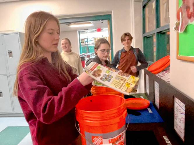 Amelia Walsh, an 11th grader, lines the waste collection buckets with newspaper after emptying the food scraps into the composters at the Hopkinton Middle High School