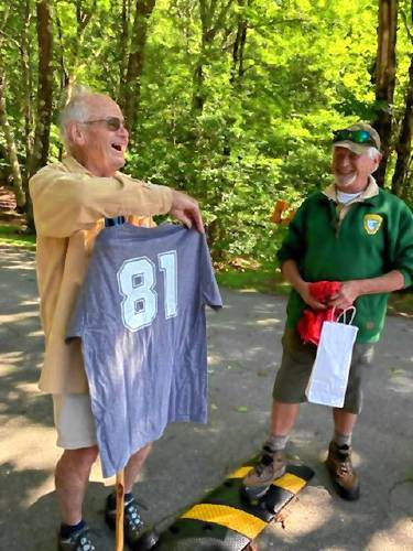 John Burke, left, receives a shirt with the number “81” to mark his 81st consecutive day hiking Pack Monadnock, for his 81st birthday.