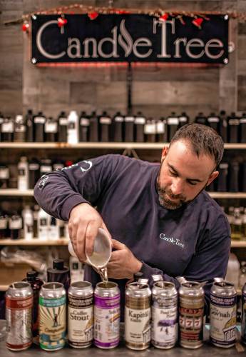 Ross Mingarelli pours the hot soy wax for his speciality beer can candles at his downtown Candle Tree Soy Candle shop in Concord.