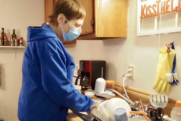 Care provided through the Choices for Independence program can include assistance with bathing, housekeeping, and cooking. Here, caregiver Joan Ilves cleans dishes in Charlestown.