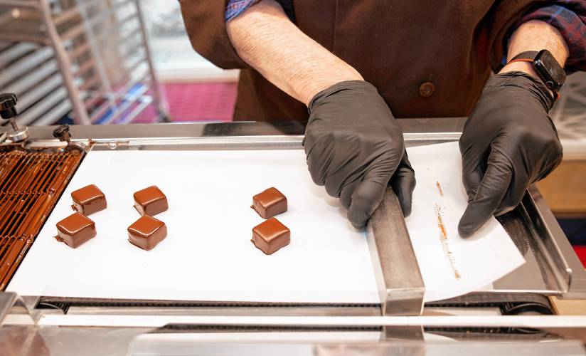 Chocolatier Jonathan Doherty uses the enrober to coat his base chocolate with another layer of chocolate at his home in Hopkinton on Tuesday, April 30.