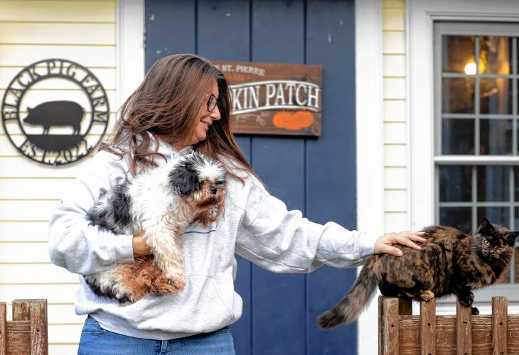 Helen St. Pierre of Old Dogs Go To Helen holds Fletch, the oldest dog she takes care of as she pets Emily, one of her barn cats at her Epsom farm.