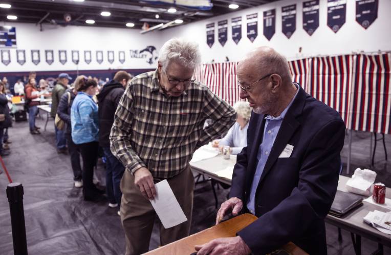 Jeff Blanchard casts his vote as assistant moderator John Herbert stands at the voting box just before the Merrimack Valley School District meeting got started in the school gym on Thursday night, March 6, 2025. Herbert was a long time Salisbury town moderator and this will be his last moderating this year.