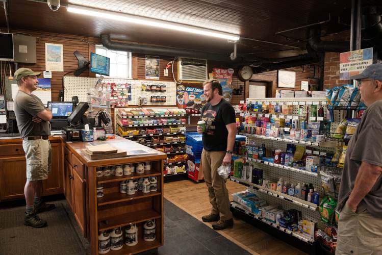 Patrick Schlott, of North Tunbridge, middle, talks with North Tunbridge (Vt.) General Store owner Michael Gross, left, and Steve Willoughby, right, after buying breakfast on July 5, 2024. “At first I thought it was a decoration,” said Willoughby of the phone. “That’s the travesty - people just put it up and say, ‘oh isn’t that cool?’” said Schlott. “My whole MO is, whether it’s an art installation or whatever, it should work.” (Valley News - James M. Patterson) Copyright Valley News. May not be reprinted or used online without permission. Send requests to permission@vnews.com.