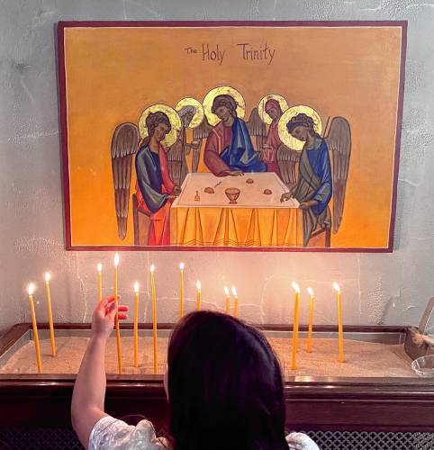 Katerina Tsihlis, 8, lights a candle in front of an icon of the Holy Trinity before the Holy Trinity Greek Orthodox Chuch’s Service of Lamentation marking the death of Christ on Holy Friday, May 3, 2024 to start the Easter weekend.