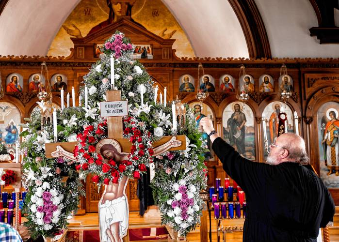 ABOVE: The Very Rev. Dr. Constantine Newman, the presiding priest at Holy Trinity Greek Orthodox Church in Concord, lights a candle on the kouvouklion, an elaborately carved canopy over the Epitaphios, which represents the tomb of Christ at the Service of Lamentation on Holy Friday. TOP: Katerina Tsihlis, 8, lights a candle.